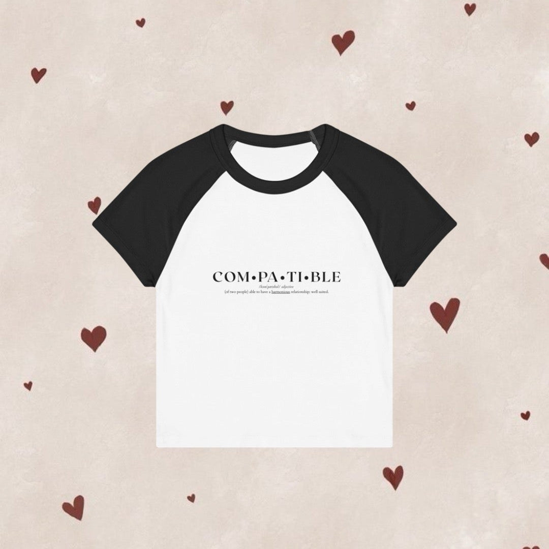 Black and white t-shirt with 'COMPATIBLE' text on a beige background with heart patterns.