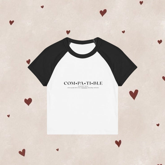 Black and white t-shirt with 'COMPATIBLE' text on a beige background with heart patterns.